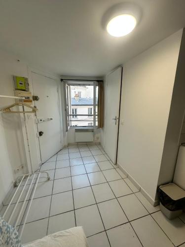 Cette chambre est dotée de carrelage blanc et d'une fenêtre. dans l'établissement STUDIO PARIS 2e ARRONDISSEMENT, à Paris