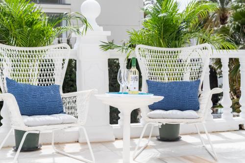 a patio with white chairs and a white table with blue pillows at Aurora Boutique Hotel - Only Adults in Marbella