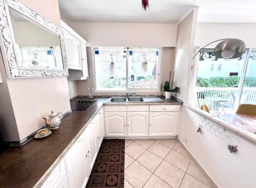 - une cuisine avec des placards blancs, un évier et 2 fenêtres dans l'établissement Positive, à Cannes