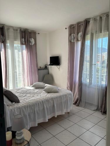 - une chambre avec un lit doté de rideaux roses et de fenêtres dans l'établissement Pietralba t3, à Ajaccio
