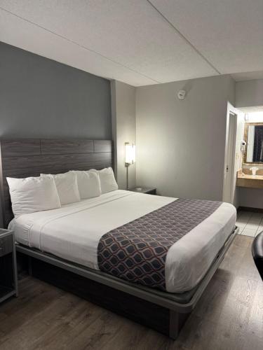 a hotel room with a large bed with white sheets at Blue Star Motel in Chicago Ridge