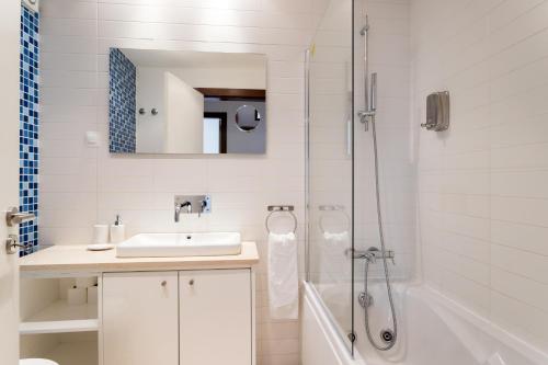 a white bathroom with a sink and a shower at Alfama Modern Two Bedroom Apartment w River View and Parking by LU Holidays in Lisbon