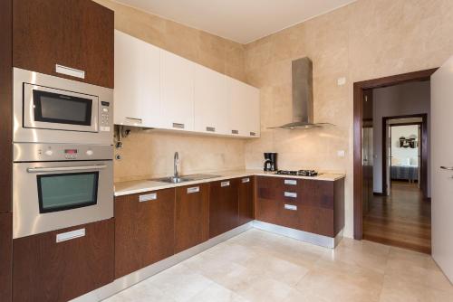 a kitchen with wooden cabinets and a stove top oven at Alfama Modern Two Bedroom Apartment w River View and Parking by LU Holidays in Lisbon