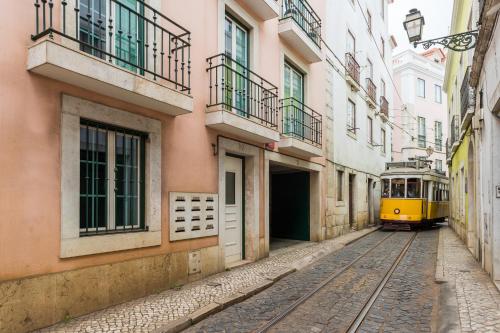 a yellow tram on a street with buildings at Alfama Modern Two Bedroom Apartment w River View and Parking by LU Holidays in Lisbon