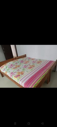 a wooden bed with a colorful blanket on it at Aswathy Bhavan in Palakkad