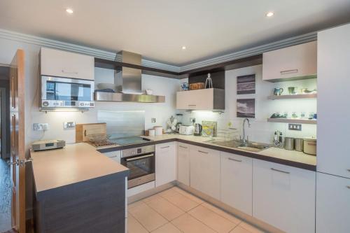 a large white kitchen with white cabinets and counters at Marina View in Cowes