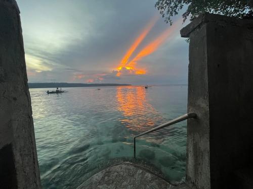 a sunset over the water with boats in the water at Villa Talisay - Beach house in Samal