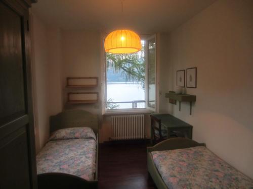 a small room with two beds and a window at Villa Eli in Lierna