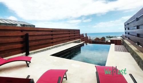 a swimming pool on the roof of a building with pink chairs at "Villa Maria" - Sublime vue Océan Classée 4 étoiles in Petite Île