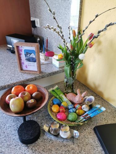 a counter with a bowl of fruit and a vase of flowers at FeWo-AdOlTi in Nittenau