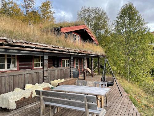 a house with a grass roof with a picnic table at Traditional Hemsedal family cabin spectacular view in Hemsedal