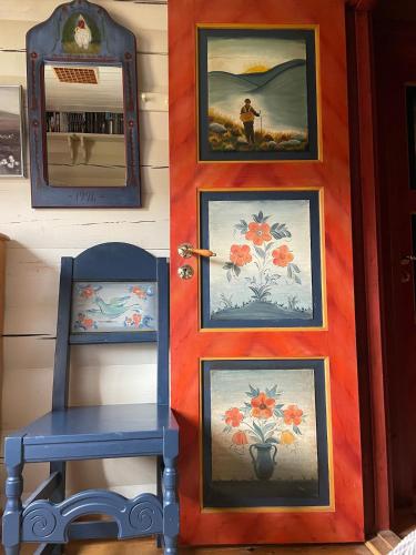 a blue chair in front of a door with paintings at Traditional Hemsedal family cabin spectacular view in Hemsedal