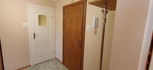 a hallway with a wooden door and a white door at Słoneczny Apartament in Szczecinek