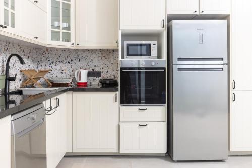 a kitchen with white cabinets and a refrigerator at Beach Vibe Villa - Sunny Stay in O Ben Slimane