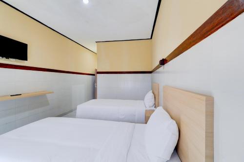 two beds in a small room with a tv at Townhouse Oak Legian Near Kuta Beach Formerly Sayang Maha Merta in Legian