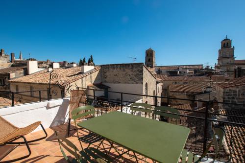 une table verte et des chaises sur un balcon avec des bâtiments dans l'établissement Donjon - Clim - Terrasse - Premium, à Arles