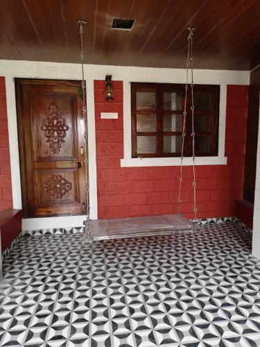 a house with a red door and a black and white tiled floor at The Mango Valley Nature's Stay in Alibag