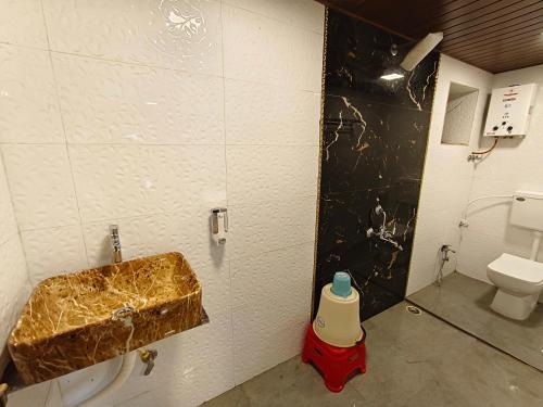 a bathroom with a gold sink and a toilet at The Mango Valley Nature's Stay in Alibag