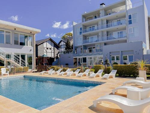 a swimming pool with lounge chairs next to a building at IQU Apart in Las Gaviotas