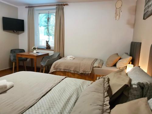 a room with three beds and a table and a window at Penzion Pohoda Sokolov in Sokolov