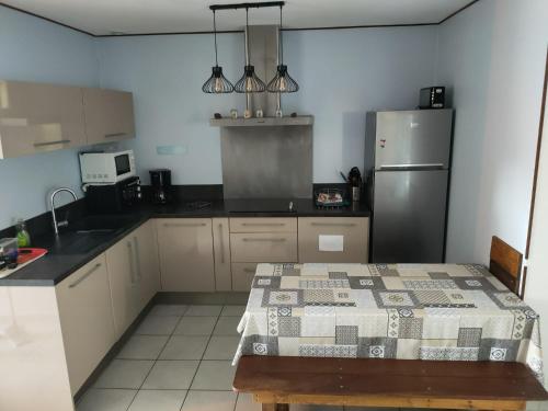 une cuisine avec un réfrigérateur et une table à l'intérieur dans l'établissement Les Jardins d’Alzetu, à Porto-Vecchio