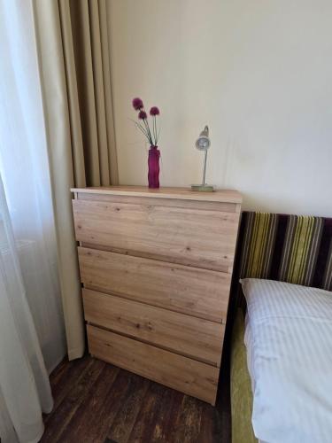 a dresser with a vase of flowers on it next to a bed at Apartment High Tatras in Veľký Slavkov