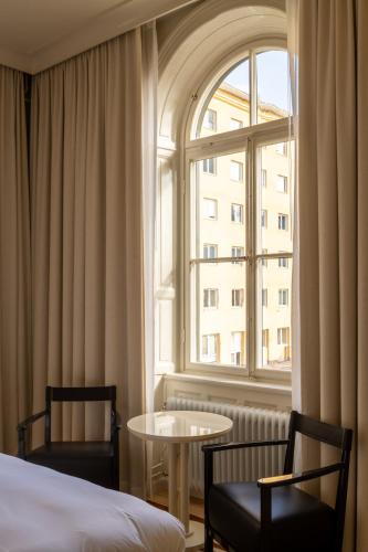 a room with a bed and a table and a window at Stockholm Stadshotell in Stockholm