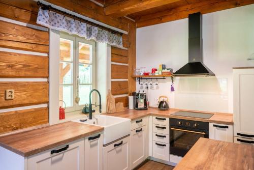 a kitchen with white cabinets and wooden walls at Roubenka pod hradem Kokořín in Kaninský Dŭl