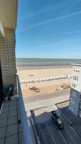 a view of a beach from a balcony with a car at Appartement vue mer in Koksijde