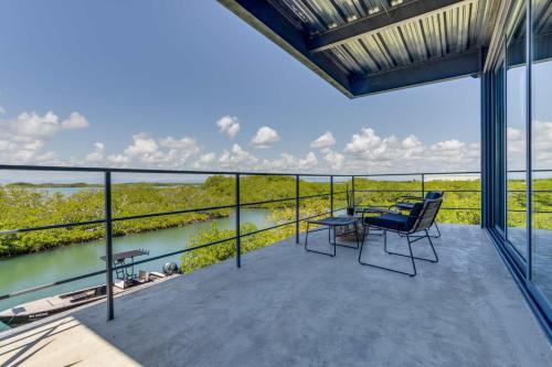 a balcony with tables and chairs and a view of a river at Casa Balam in Placencia Village
