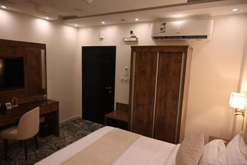 a bedroom with a bed and a desk and a door at فندق فيوليت الفندقية Violet Hotel in Yanbu