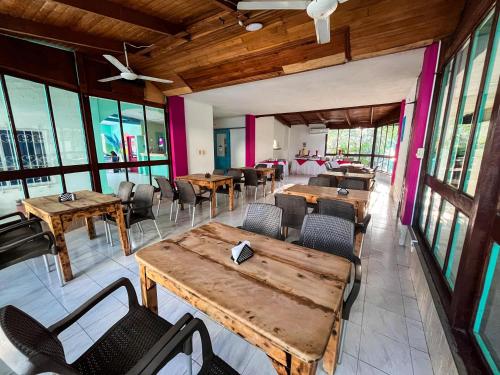a restaurant with wooden tables and chairs and windows at Hotel Los Veleros Santa Marta in Santa Marta