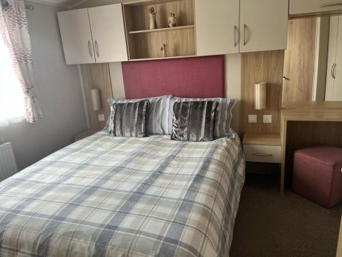 Un dormitorio con una cama con una manta azul y blanca. en Woodend Caravan, en Shinness
