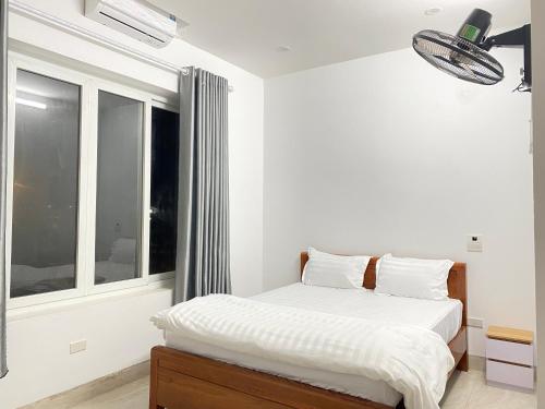 a white bedroom with a bed and a window at Tamcoc Motel in Văn Lâm