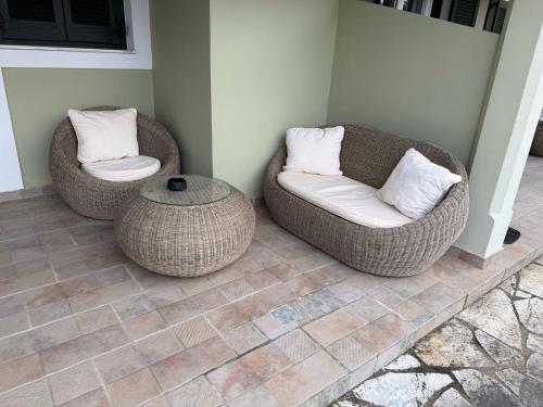two wicker chairs and a table on a patio at Sidari Vibes On The Beach in Sidari