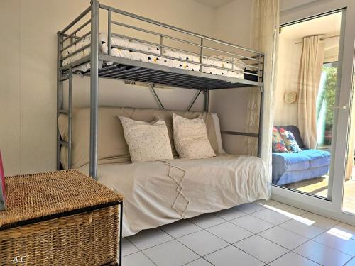 une chambre avec un lit superposé dans une pièce dans l'établissement Le Murier - Rez de jardin avec véranda, terrasse à 5min a pied de la mer avec parking - BY AURAconciergerie, aux Lecques