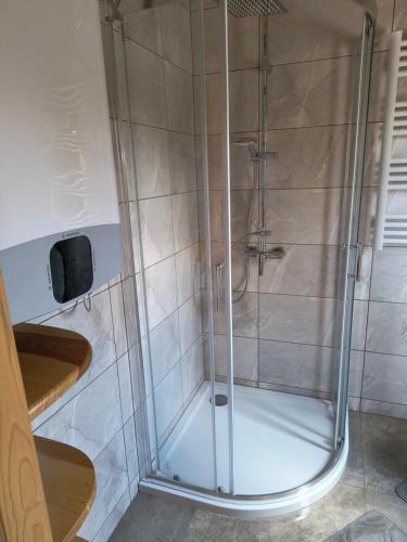 a shower with a glass door in a bathroom at Noclegi nad stawami wypożyczalnia kajaków i rowerów in Milicz