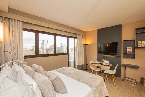 a hotel room with a large bed and a table at APS - Alpha Stay By Anora Spaces in Barueri