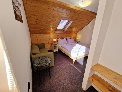 a small attic room with a bed and a chair at Vila Pramínek, Horní Maršov, Krkonoše in Horní Maršov
