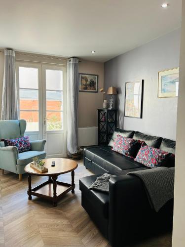 a living room with a black couch and a table at Home St. Germain in Trouville-sur-Mer