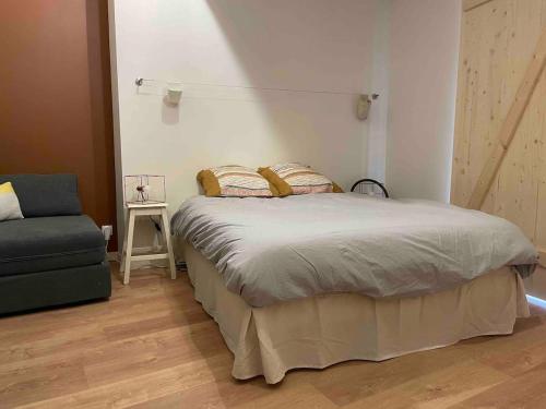 a bedroom with a large bed and a chair at Chambres - Ancien domaine de Chartreux in Tullins