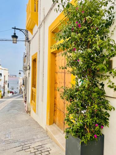 a building with a yellow door and a plant at La Botica Home in Níjar
