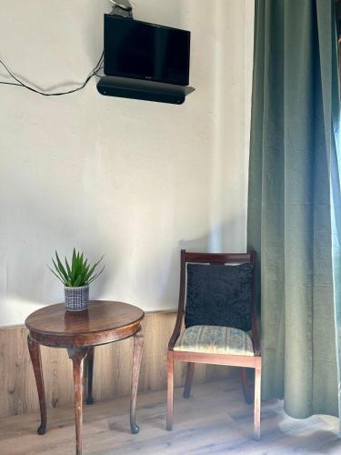 a chair and a table with a tv on a wall at Monte Sinai Guest House in Porto