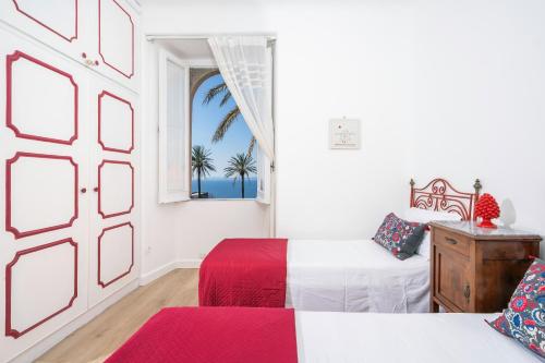 a white room with two beds and a window at Sunset House Costiera Sorrentina in Vico Equense