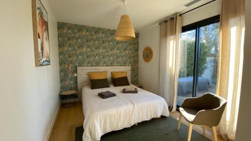 une chambre avec un lit, une chaise et une fenêtre dans l'établissement Villa des Pins, à Andernos-les-Bains