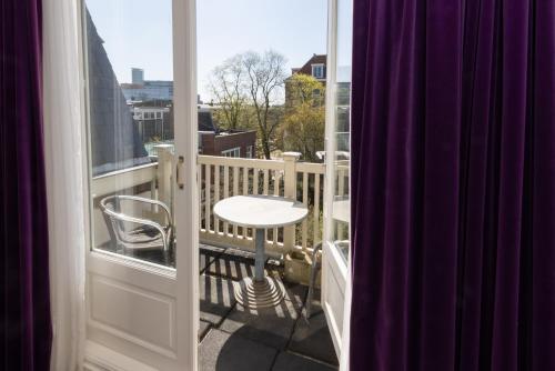 a balcony with a table and a stool on a balcony at Irene's Palace - The Hague Scheveningen in The Hague