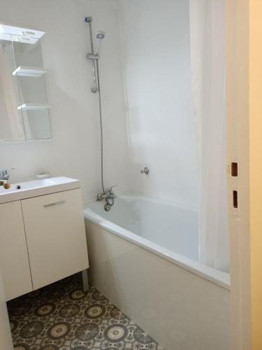 une salle de bain blanche avec une baignoire et un lavabo dans l'établissement Charmant triplex avec jardin, proche des plages, à Lège-Cap-Ferret