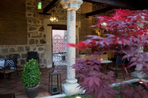 a column in a patio with a table and chairs at Hotel Las Cancelas in Avila