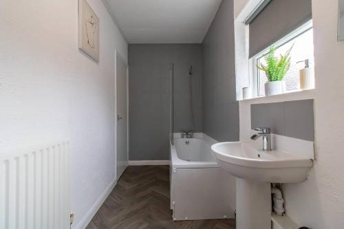 a white bathroom with a sink and a bath tub at Coastal Comfort Haven 3BR Retreat in South Shields