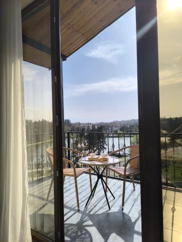 a patio with a table and chairs on a balcony at Lake House in Tskaltubo